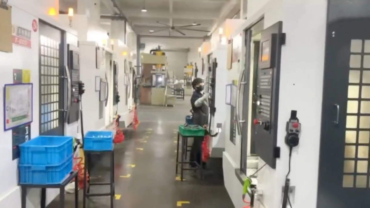 Operator checking CNC machining equipment settings for milled parts