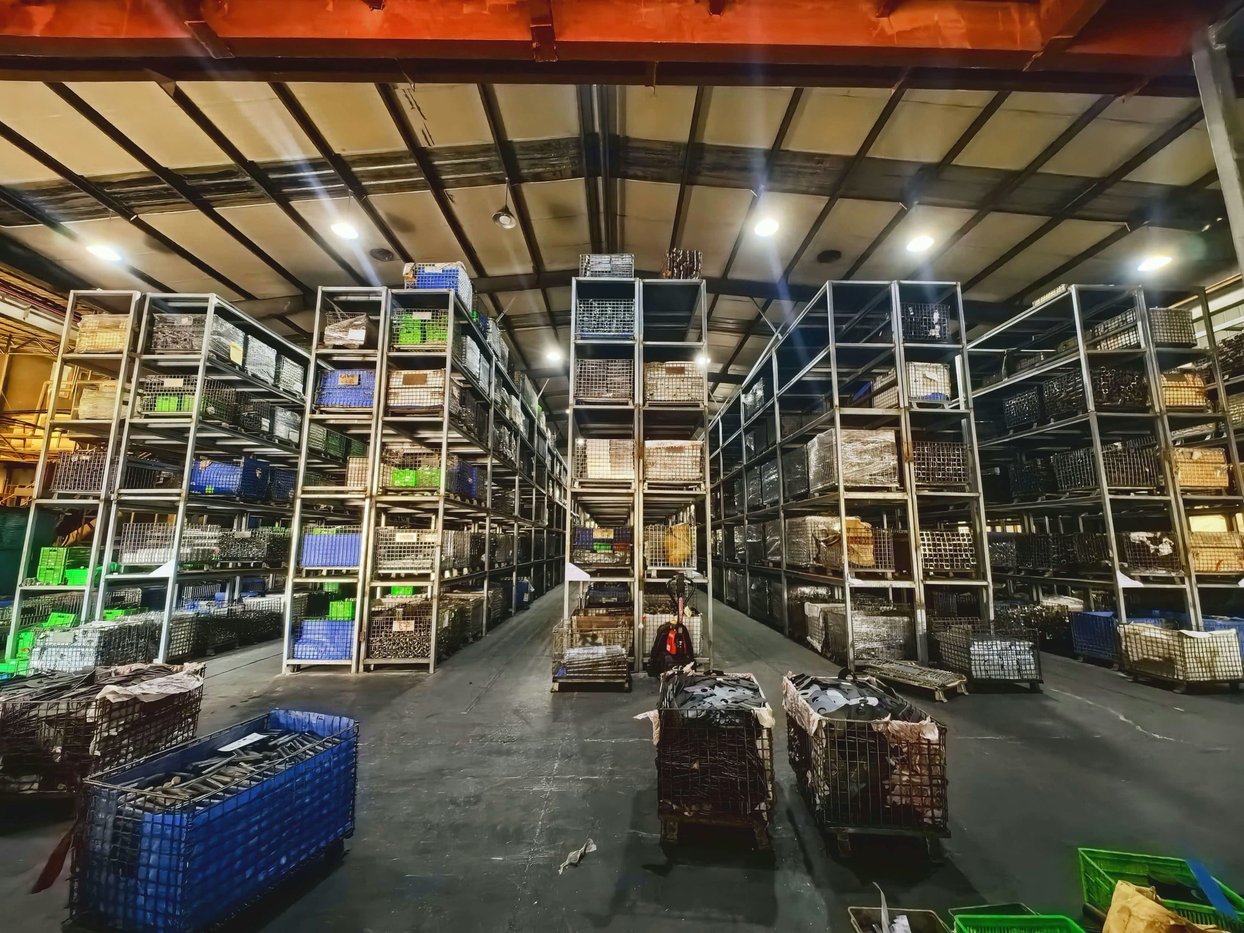Aisles between tall NBFEIYU warehouse racks holding wire baskets and component bins